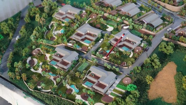 A lush residential community with modern houses, swimming pools, and landscaped gardens.
