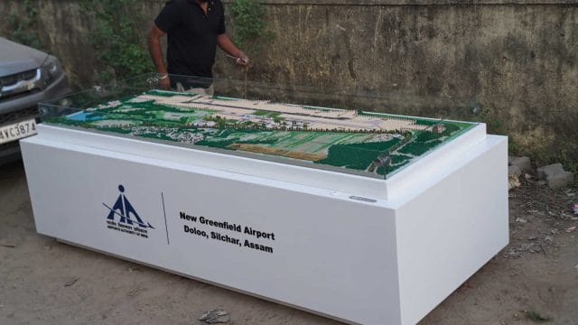 A detailed model of Dolo Airport, Silchar, Assam, displayed outdoors with a person observing it.
