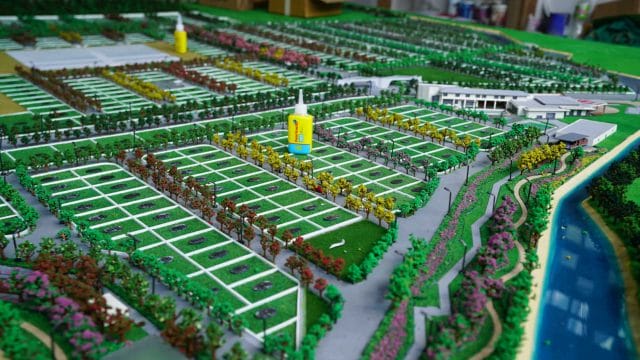 Brightly colored model of a residential community with organized plots, lush landscaping, and water.