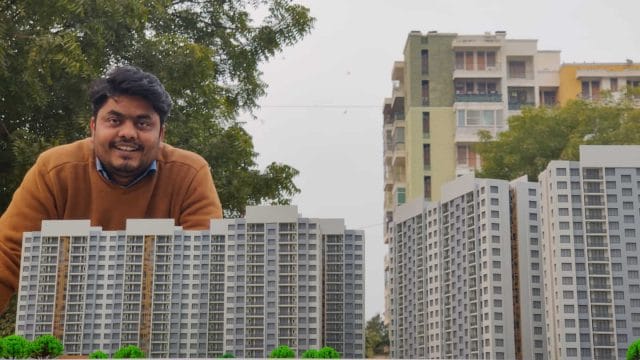 A lush green cityscape with modern high-rise buildings and a smiling man in the foreground.