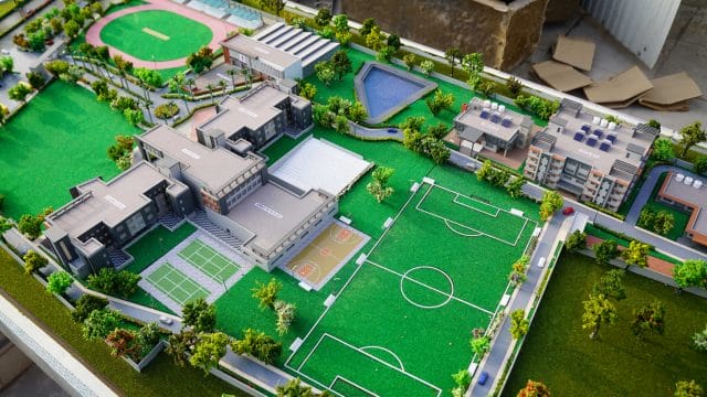 Detailed scale model of Shalom International School with sports fields and playgrounds.
