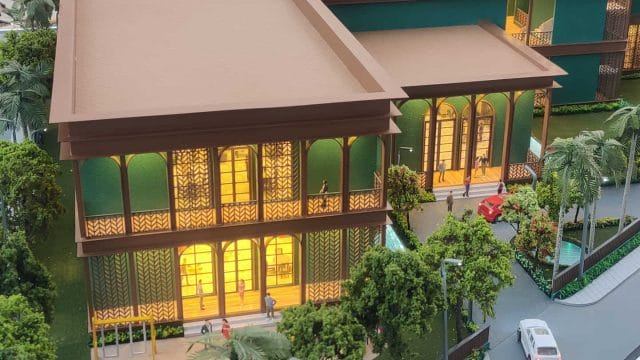 Modern green and brown residential building with lush landscaping and street view.