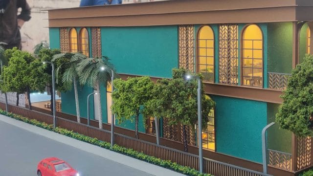 Modern building with colorful exterior, trees, and street view in Mangalam Rambhag Club area.