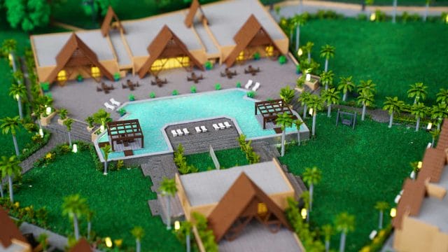 A lush resort with traditional thatched-roof cottages and a central swimming pool, surrounded by tro.